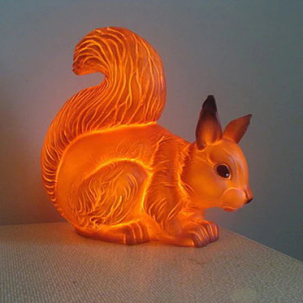 A squirrel shamped lamp.  The lamp is on and gives off a soft warm yellow glow.