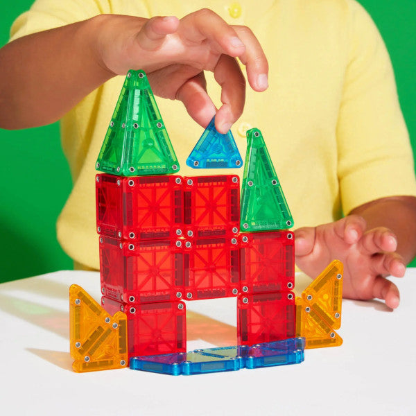 a child is building a structure from small mini sized magnet tiles